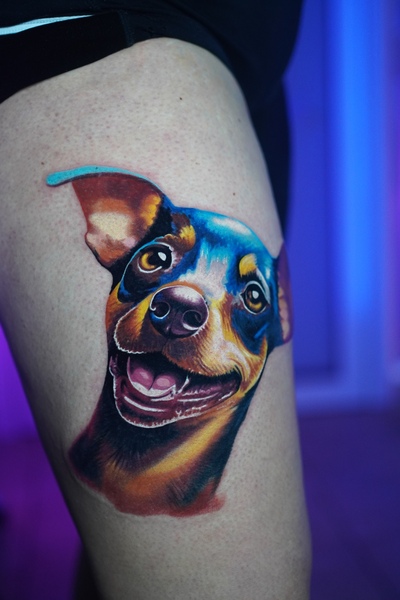 Farbiges Tattoo eines Hundes auf dem Oberschenkel.