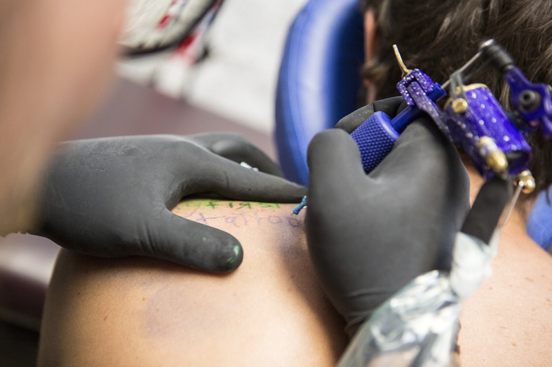 Tätowierer sticht ein Tattoo mit einer Maschine.