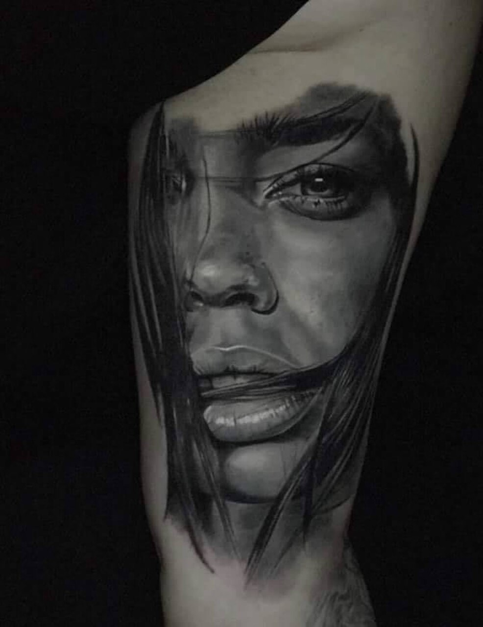 Ein realistisches Schwarz-Weiß-Portrait-Tattoo eines Gesichts mit intensiven Details und Schattierungen.